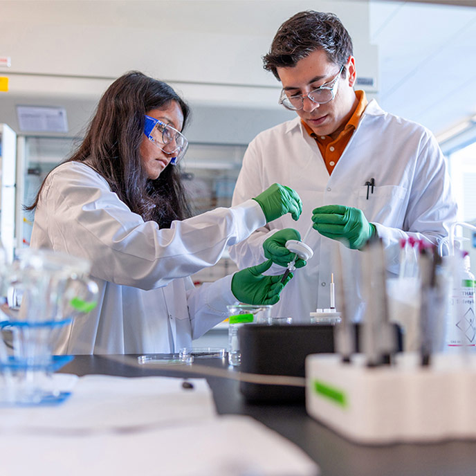 two students wearing protective gear in a lab setting